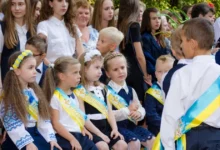 Дитина з рюкзаком, яку фотографують на шкільному подвір’ї